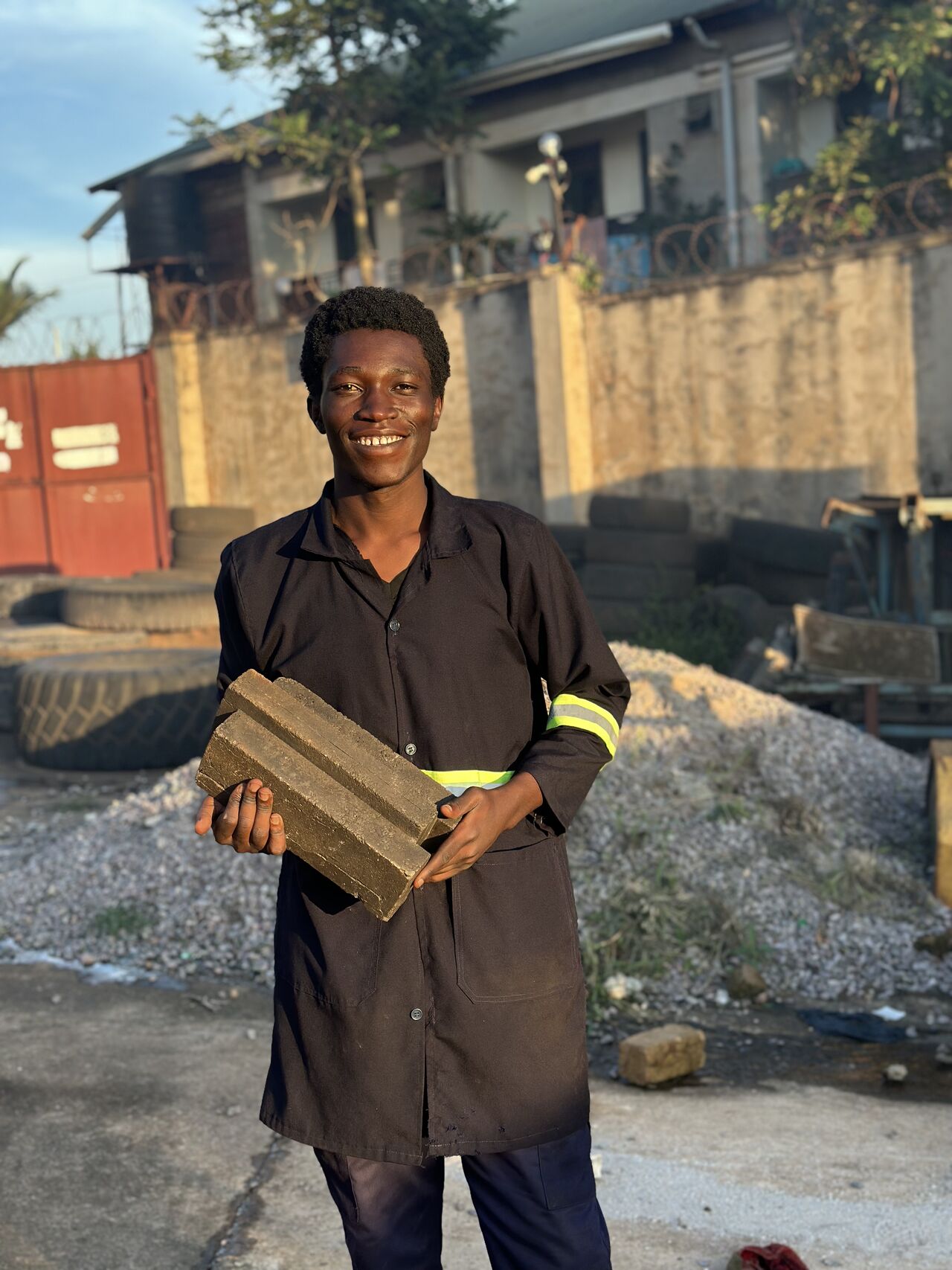 Circular Build Africa team member holding a recycled plastic building block